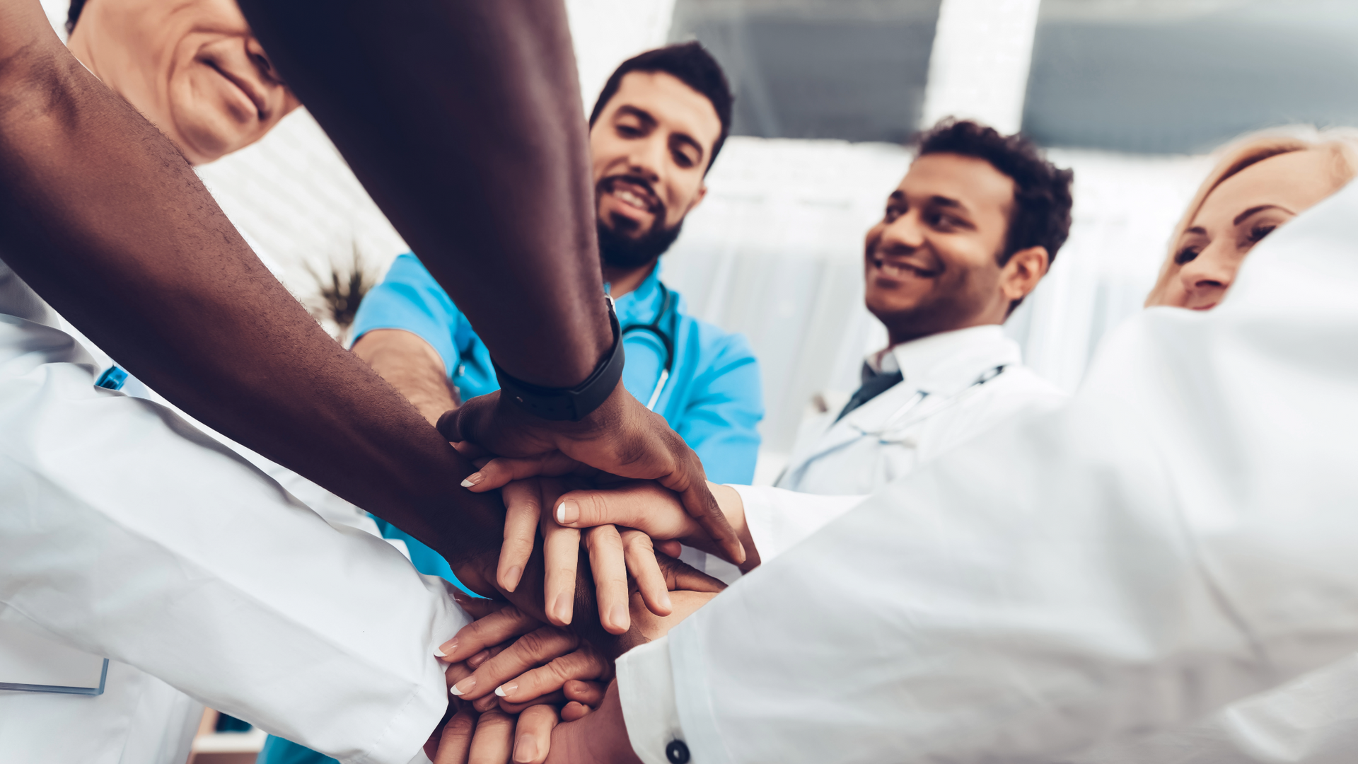 A group of doctors and nurses are putting their hands together.