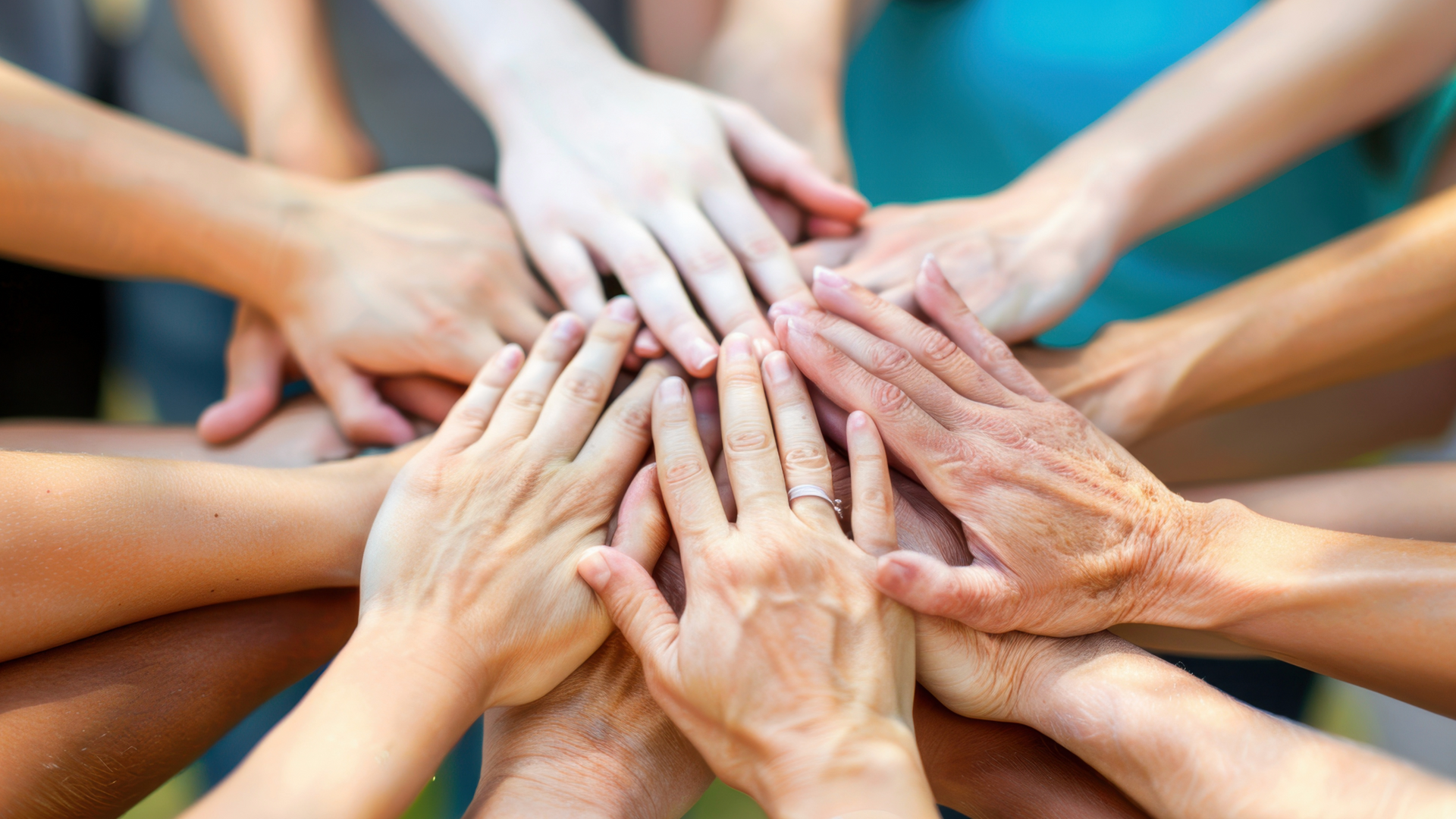 A group of people are putting their hands together in a circle.