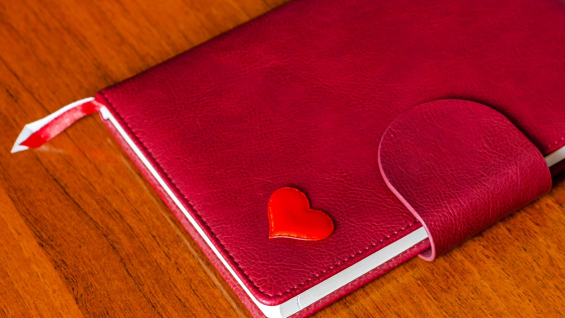 Red note book with red heart emblem on bottom right corner