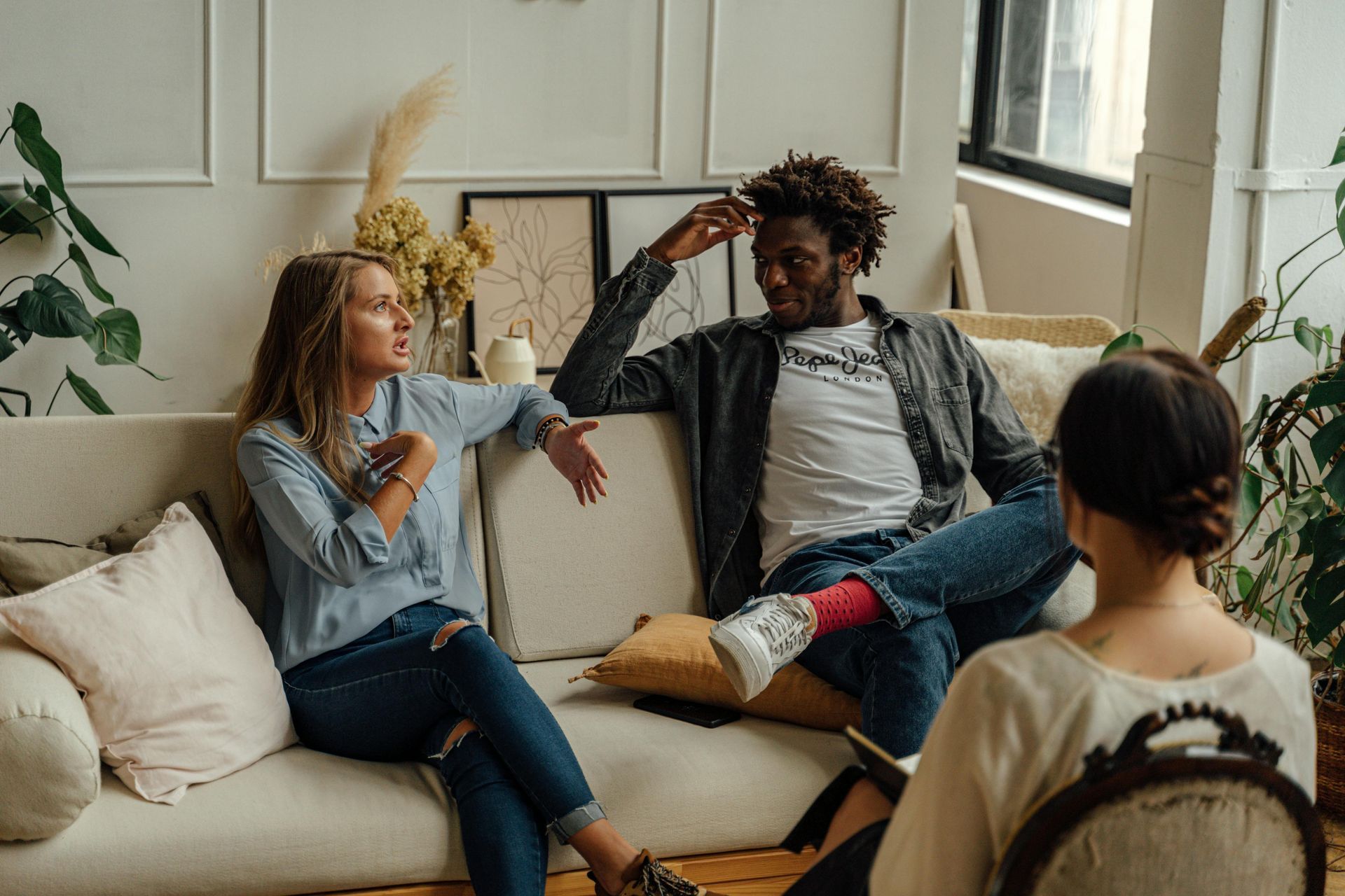 A man and a woman are sitting on a couch talking to a woman.