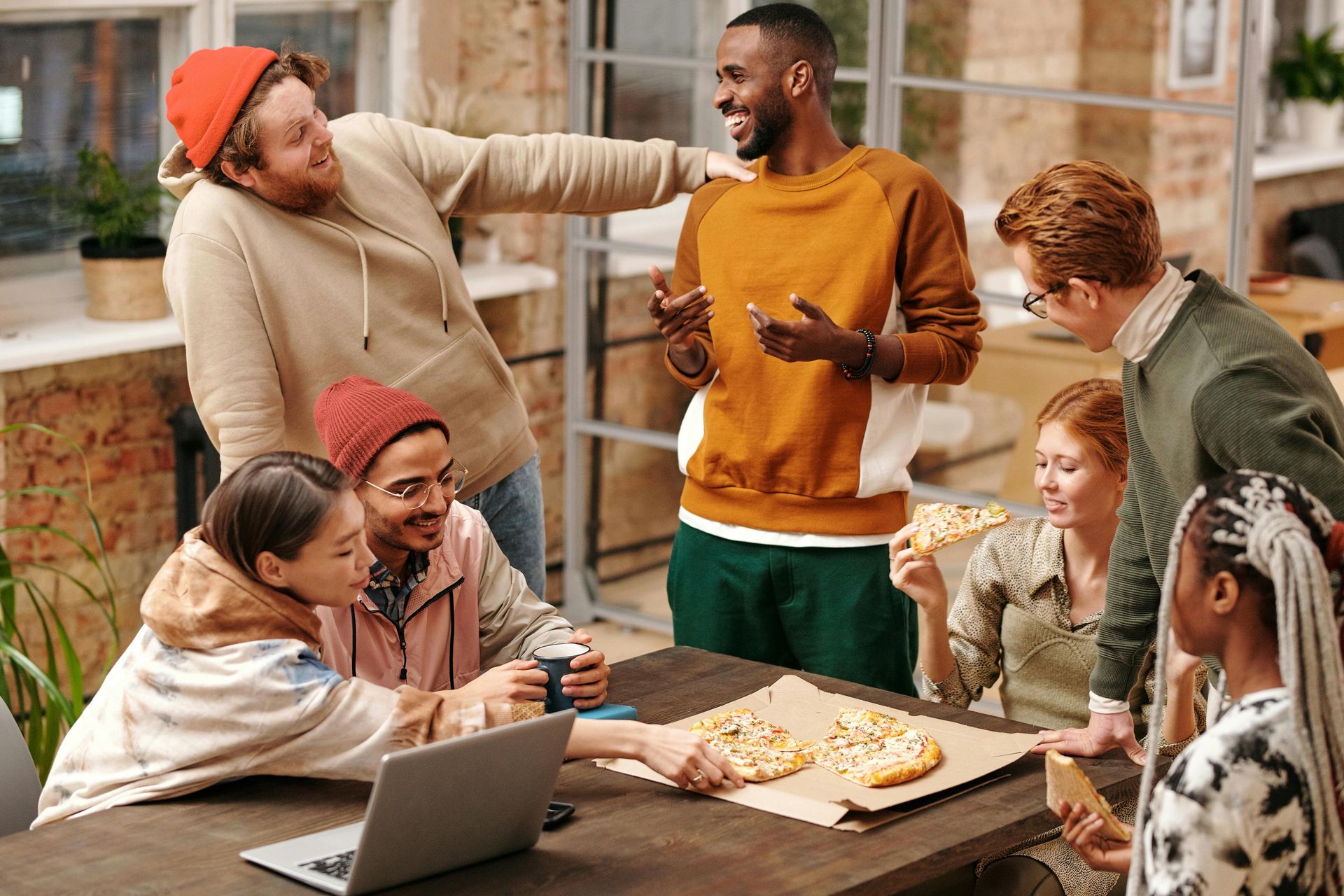 A group of people are sitting around a table eating pizza.