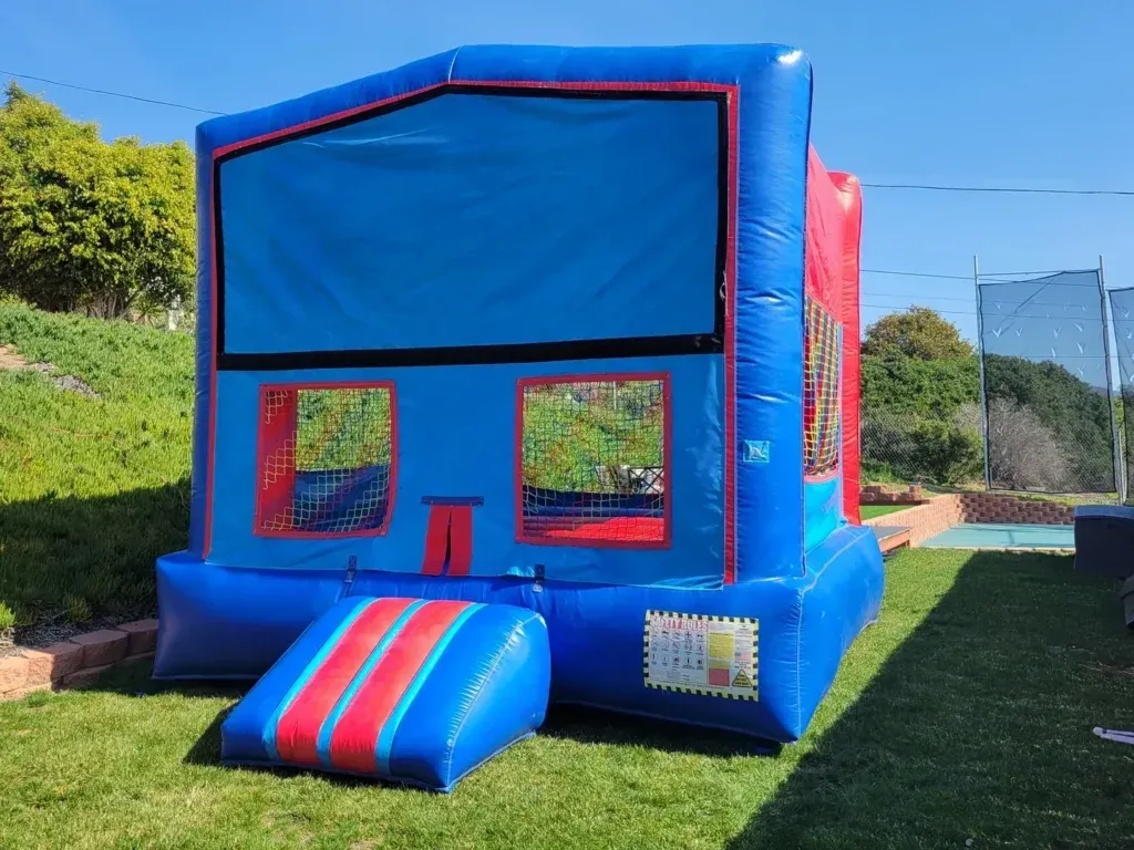 Blue and red inflatable bounce house on a grassy lawn outdoors
