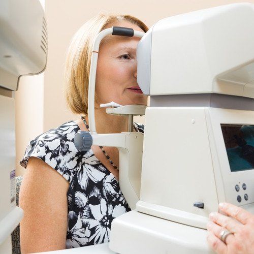 Female optician examining patient's eye pressure with tonometer