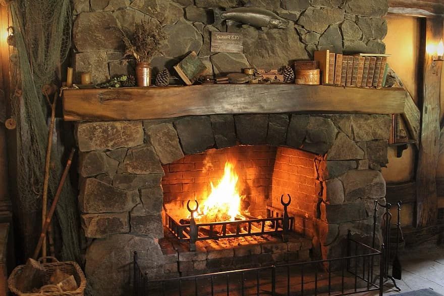 Stone fireplace with a roaring fire, rustic setting.