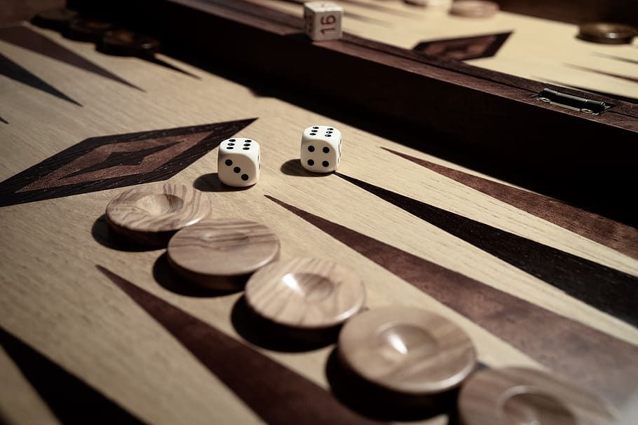 Backgammon board with dice showing a 1 and 3, wooden checkers, close-up shot.