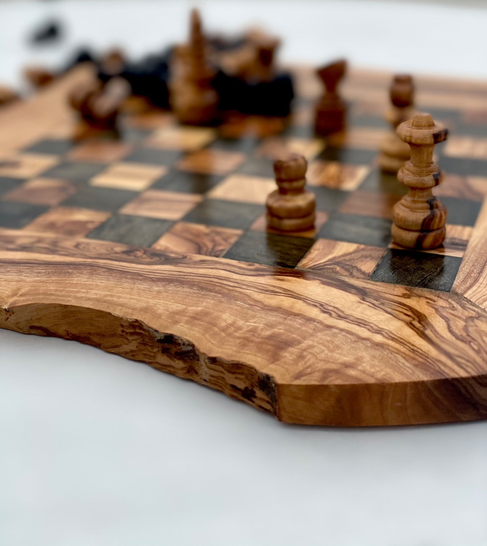 Wooden chess board with olive wood edge, pieces in play.