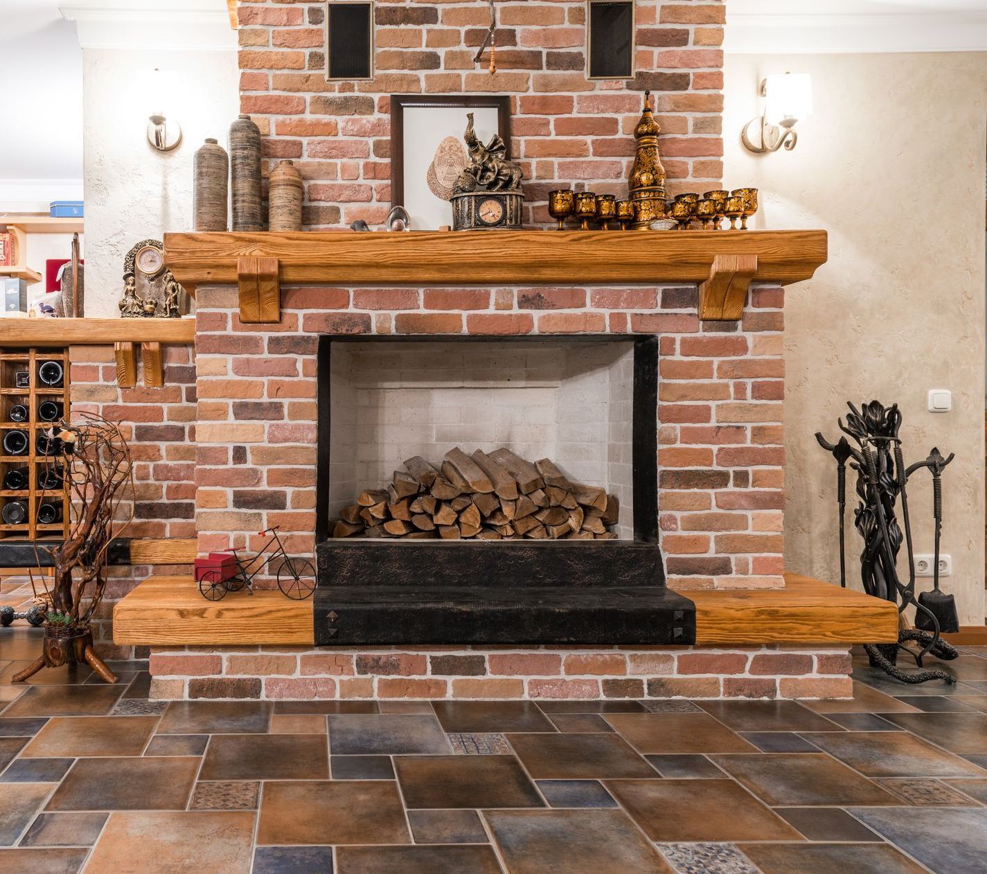 Brick fireplace with wooden mantel, holding decorations. Firewood inside.