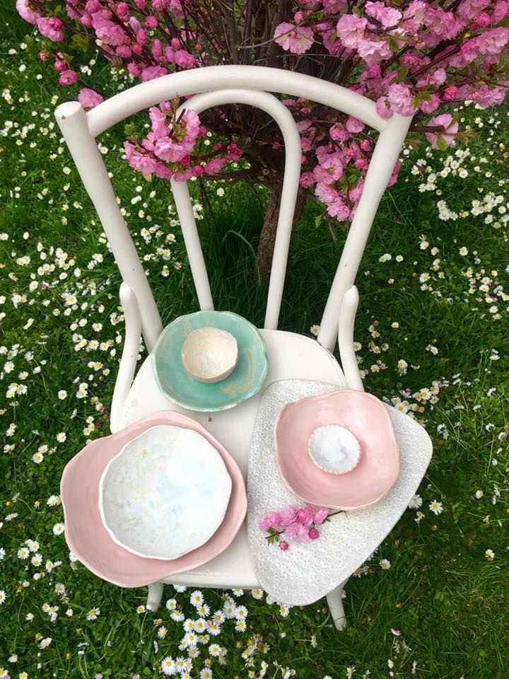 Ein weißer Stuhl mit drei Schüsseln darauf vor einem Baum mit rosa Blüten.