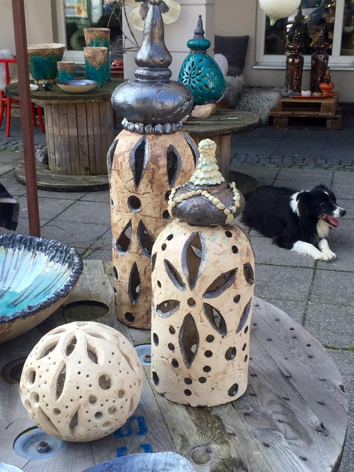 Ein Hund liegt auf dem Bürgersteig neben einem Holztisch mit Keramik darauf.