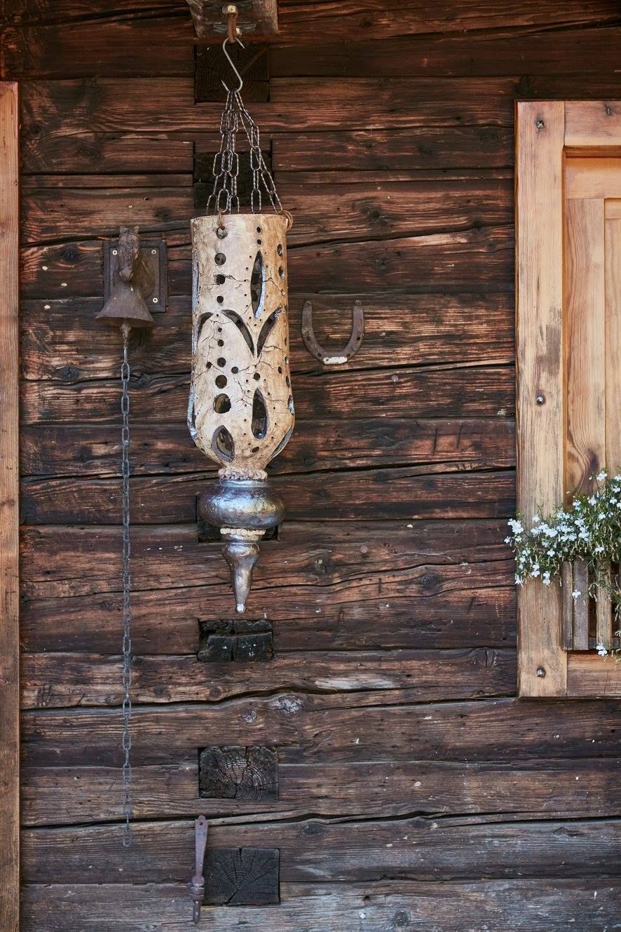 Eine Holzwand mit einer daran hängenden Laterne und einem Fenster.