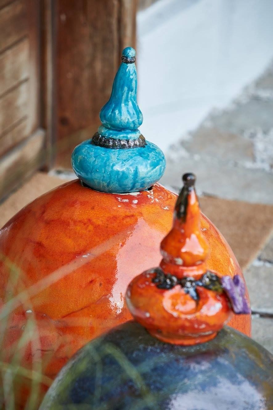 Eine Nahaufnahme einer Keramikskulptur mit blauer Spitze, die auf einem Tisch steht.