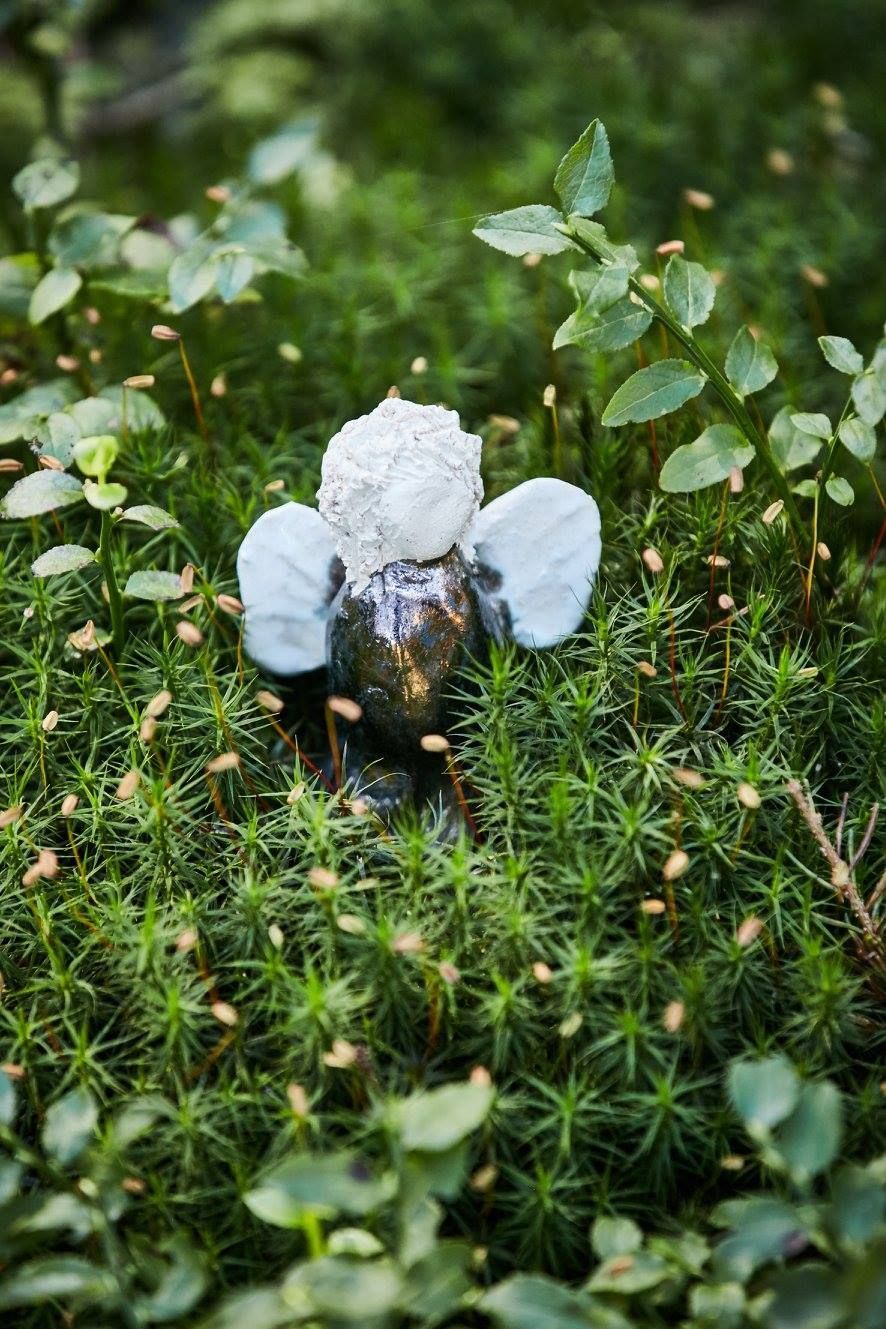 Im Moos sitzt eine kleine Engelsstatue.