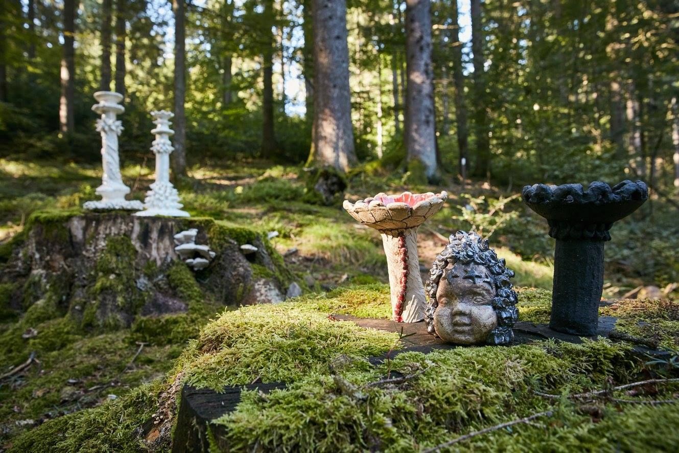 Eine Igelstatue, die auf einem moosigen Baumstumpf im Wald liegt.