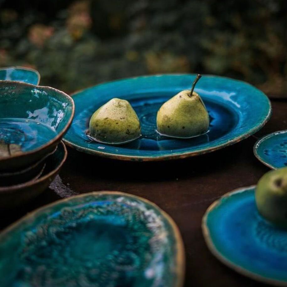 Zwei Birnen liegen auf einem blauen Teller auf einem Tisch.