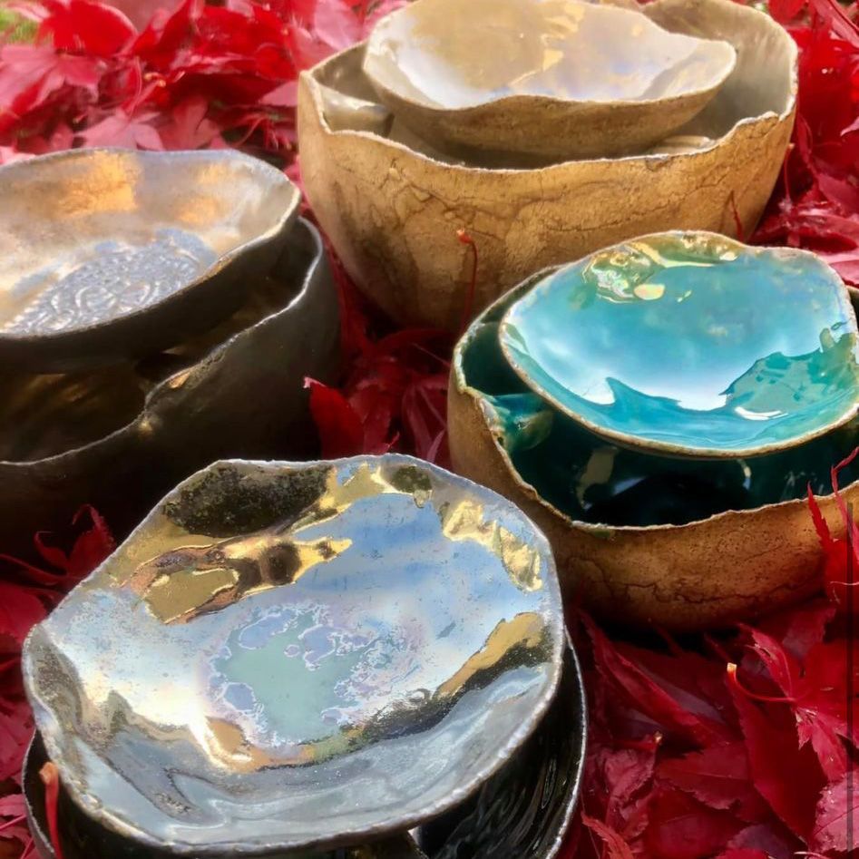 Auf einem Haufen roter Blätter sind vier Schüsseln übereinander gestapelt.