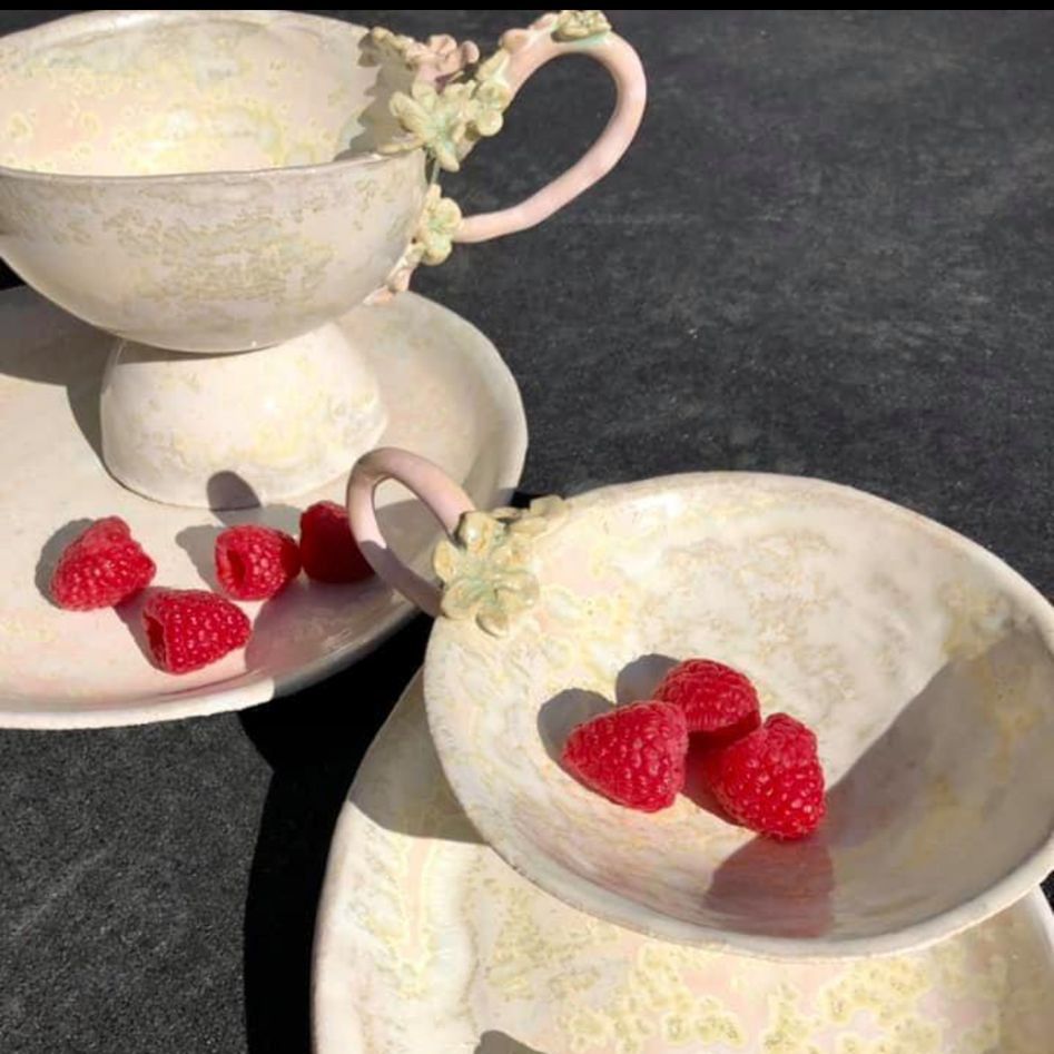 Zwei Tassen und Untertassen mit Himbeeren darauf