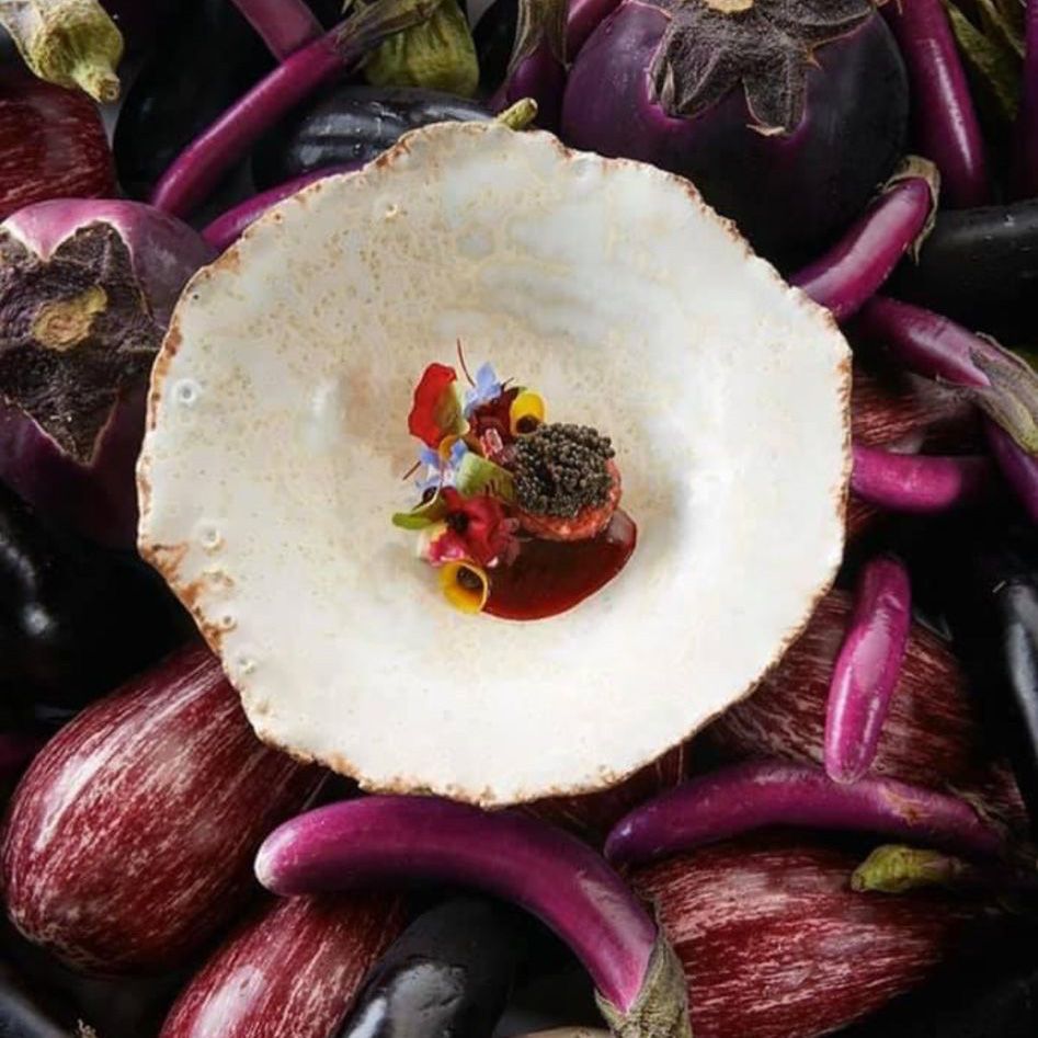 Eine Schüssel mit Essen ist von violetten Auberginen umgeben