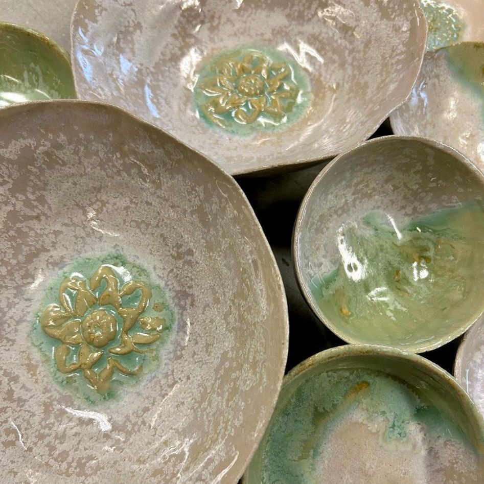 Auf einem Tisch steht eine Gruppe von Schalen mit Blumen darauf.