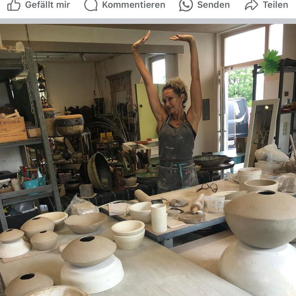 Eine Frau in einem Töpferstudio mit ihren Armen in der Luft