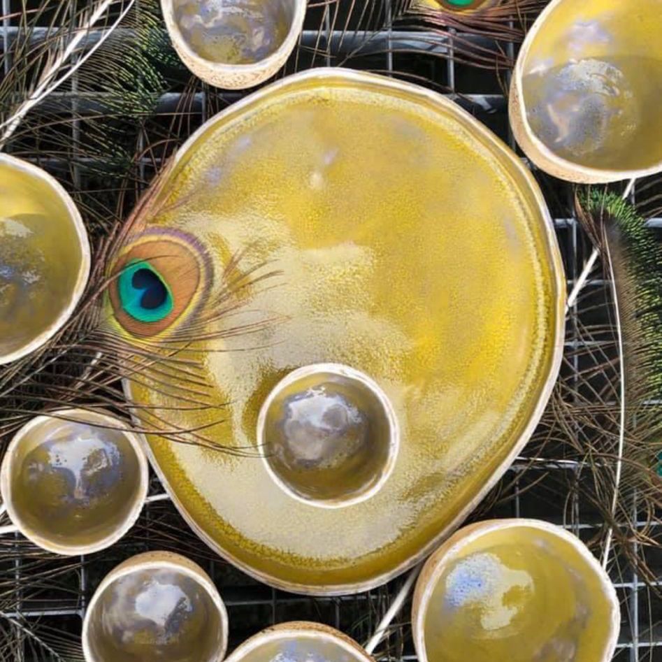 Ein gelber Teller mit einer Pfauenfeder darauf