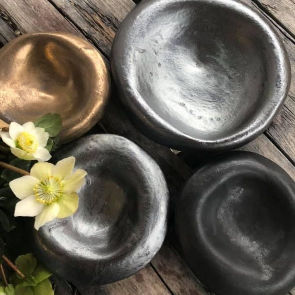 Drei Schüsseln stehen neben Blumen auf einem Holztisch.