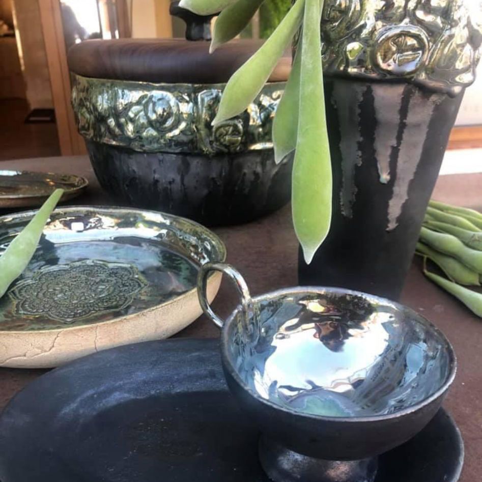 Eine silberne Schüssel steht auf einem Tisch neben einer Topfpflanze