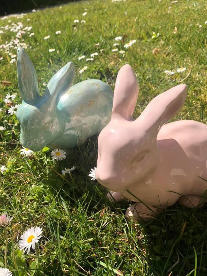 Zwei Keramikhasen sitzen im Gras.