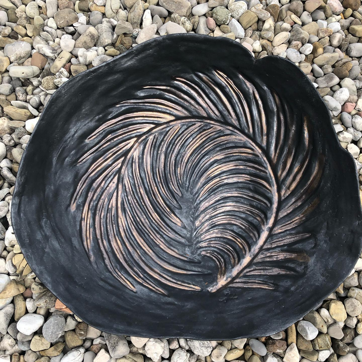 Ein schwarzer Teller mit einem Federmuster darauf