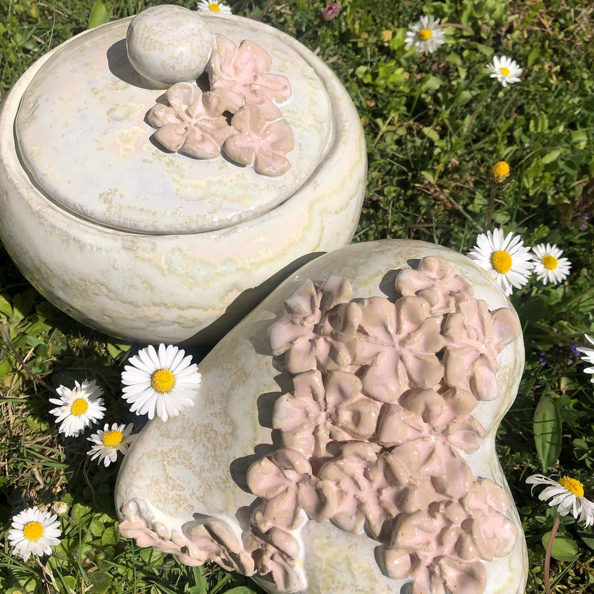 Ein paar Skulpturen, die auf einem üppigen grünen Gänseblümchenfeld sitzen.