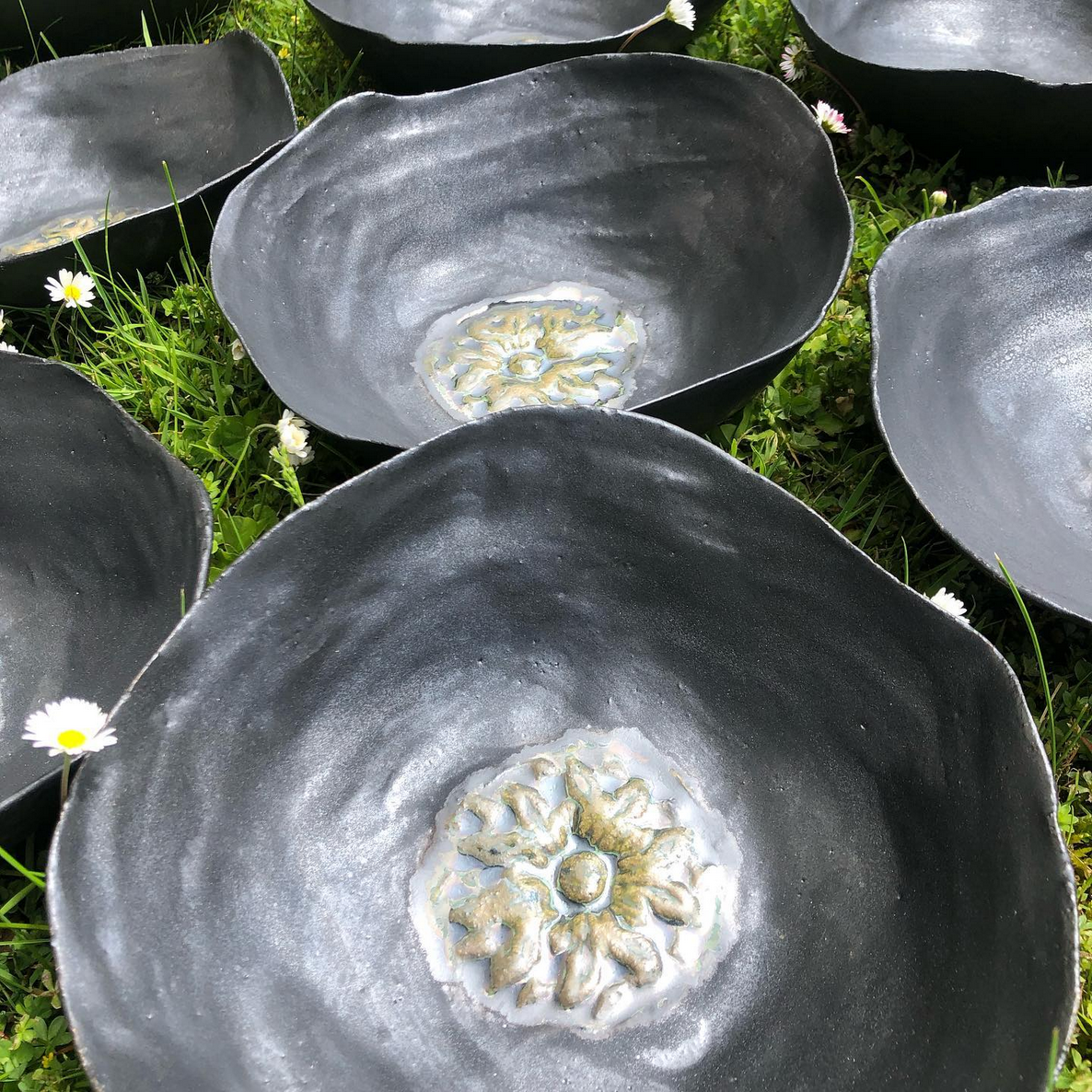 Eine Gruppe schwarzer Schüsseln steht übereinander im Gras.