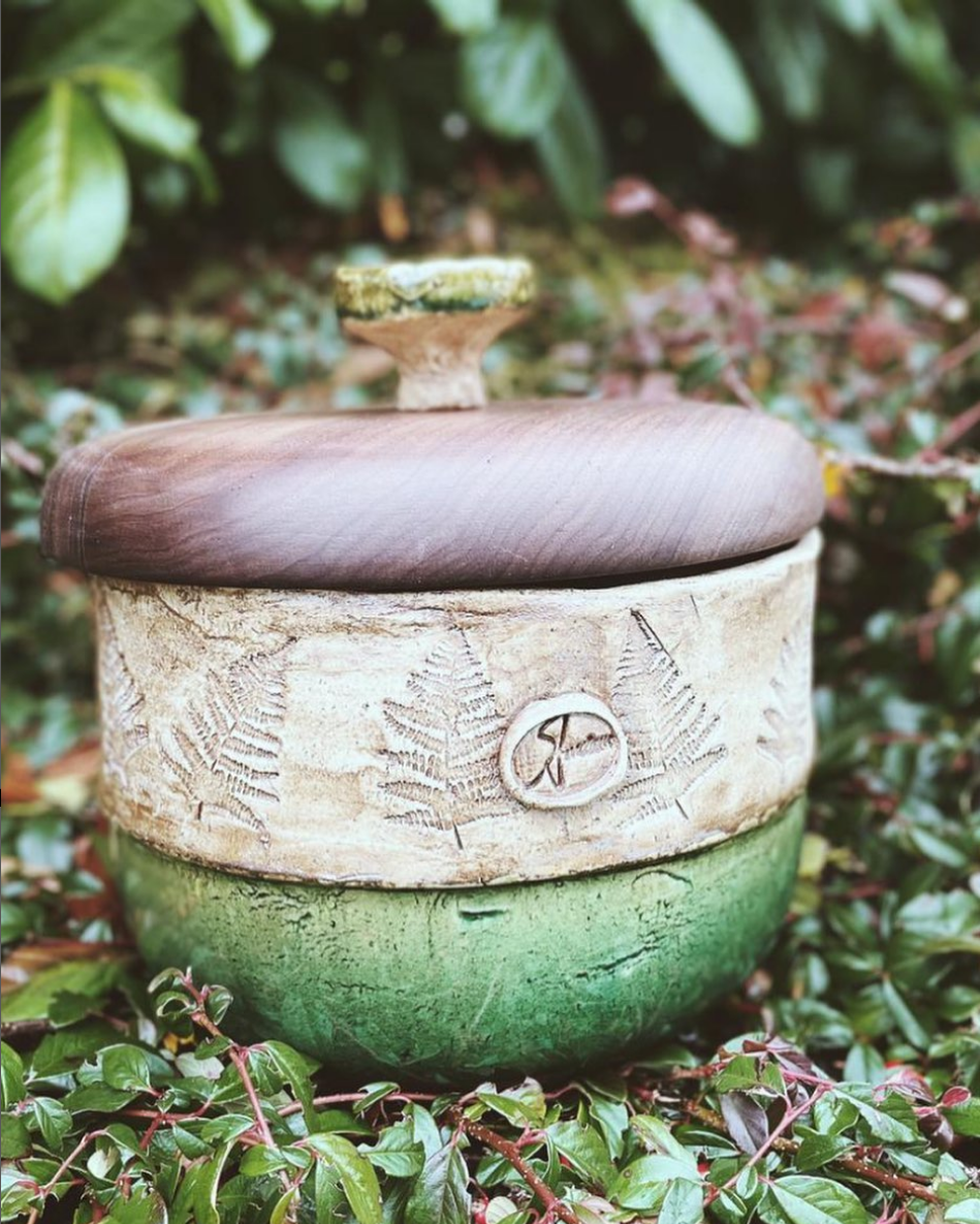 Auf dem Boden steht eine grün-weiße Schüssel mit Holzdeckel.