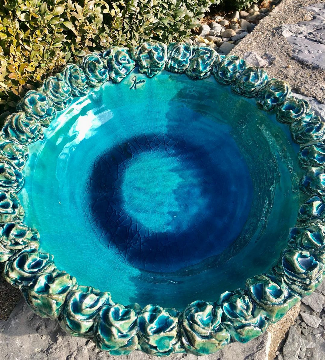 Auf einem Felsen steht eine blau-grüne Schüssel.