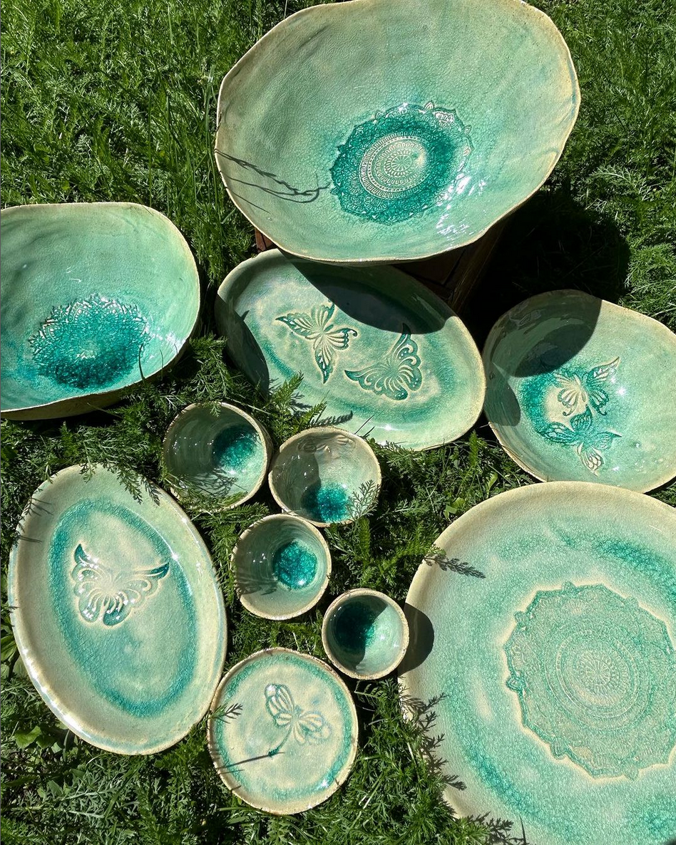 Mehrere Teller und Schüsseln stehen übereinander im Gras.