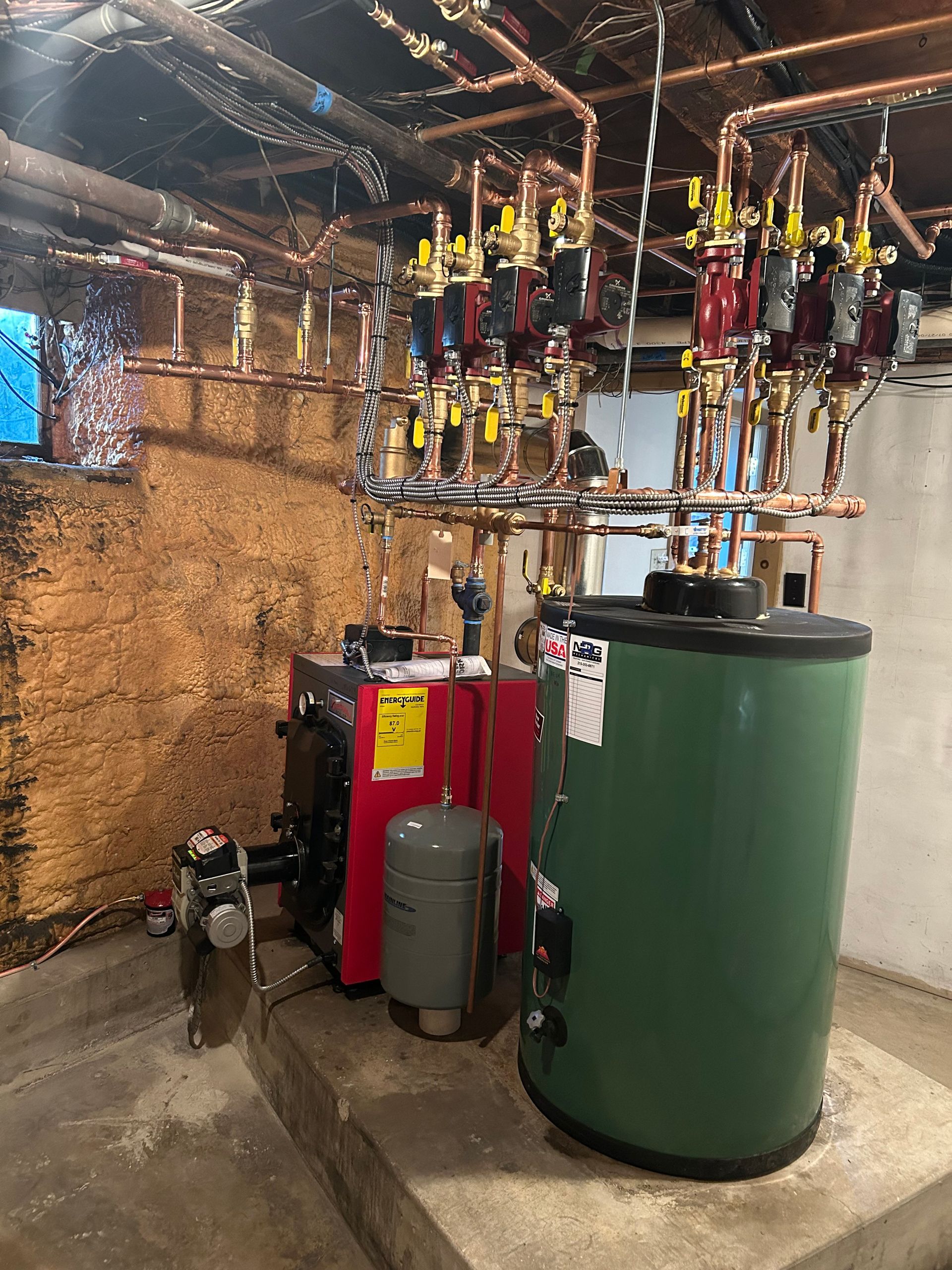A Green Water Heater is Sitting Next to a Red Boiler in a Basement