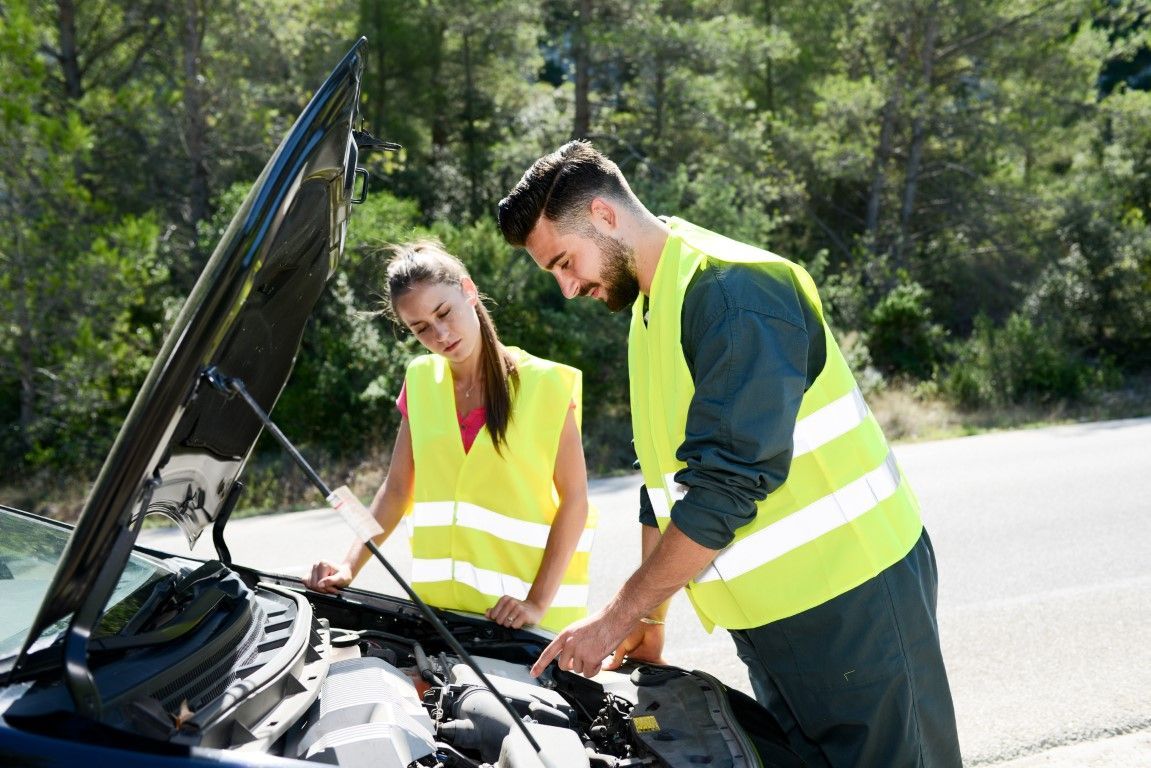 Two technicians examining a roadside vehicle with open  hood