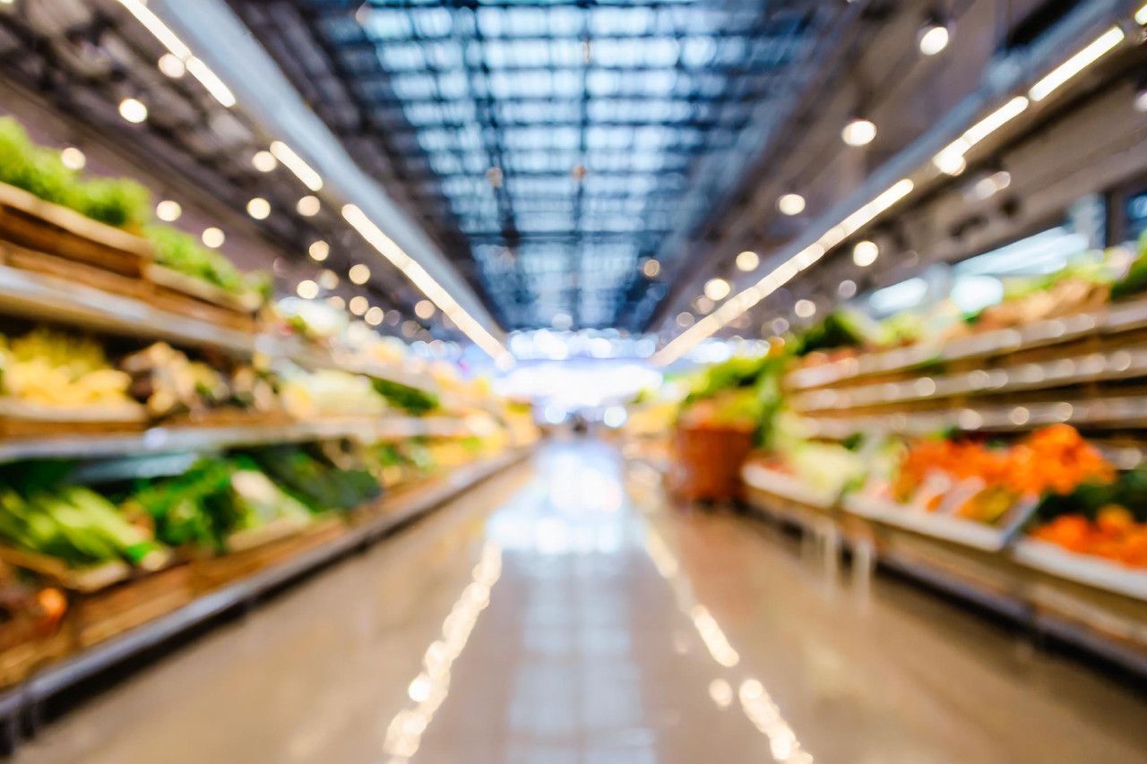 Uma imagem borrada de um corredor de supermercado cheio de frutas e vegetais.