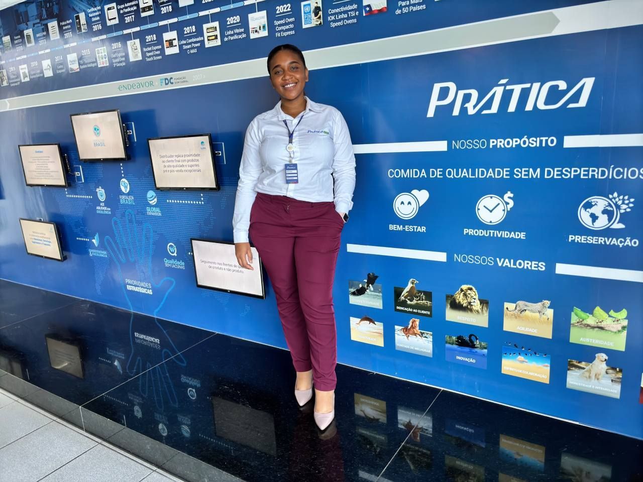 Uma mulher está parada em frente a uma parede que diz prática