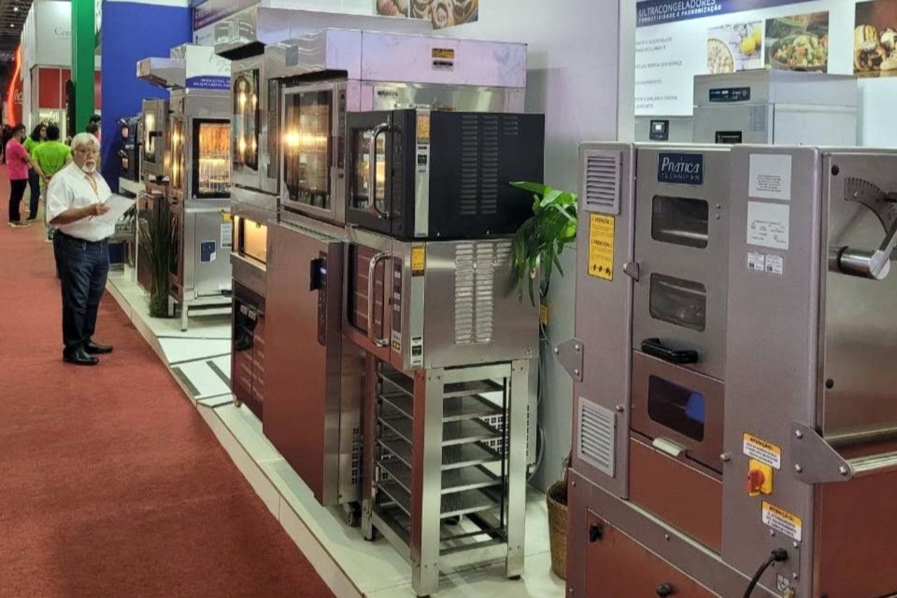 Um homem está em pé em frente a uma exposição de fornos de aço inoxidável.