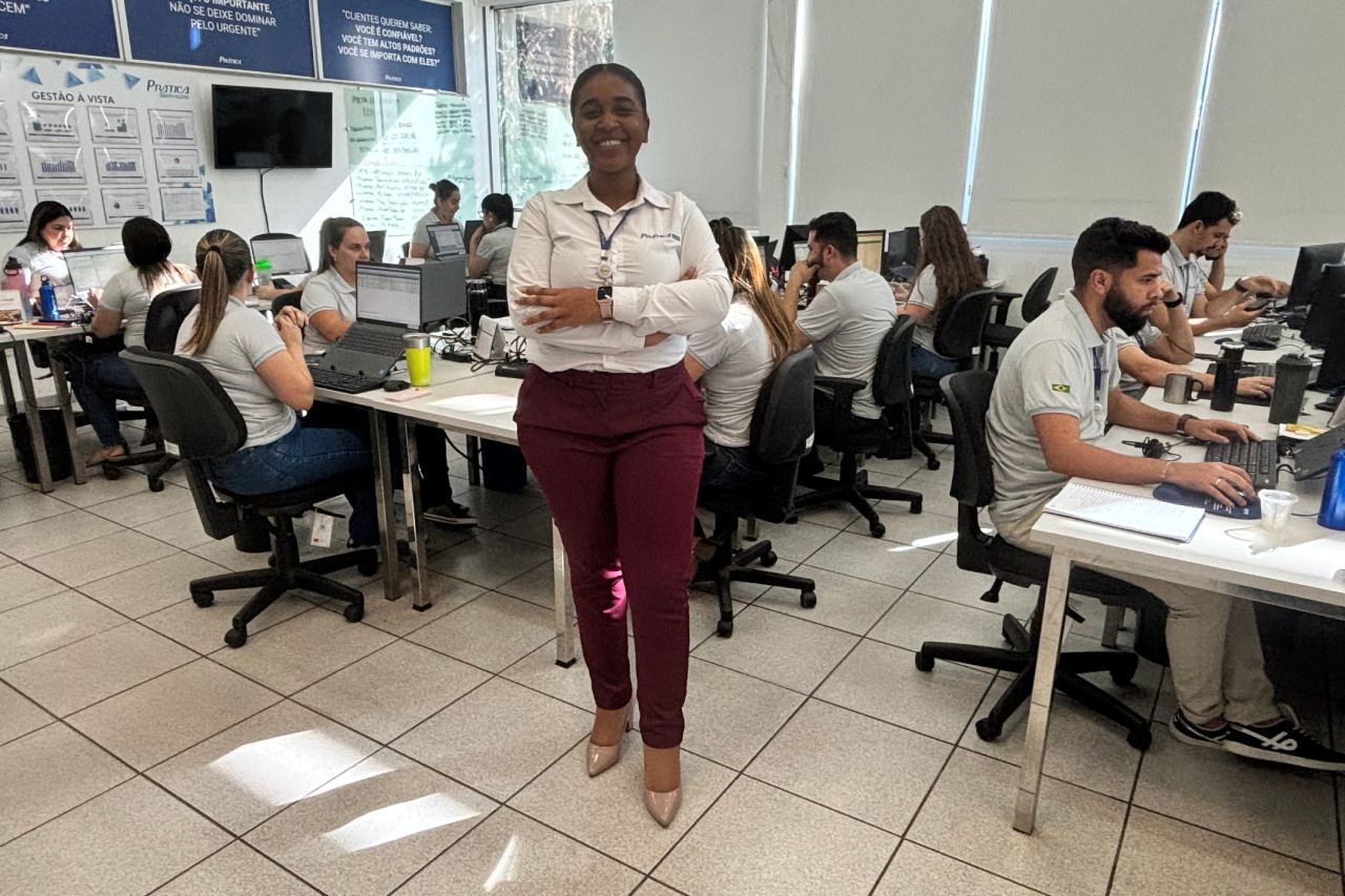 Uma mulher está de pé em um escritório com os braços cruzados.