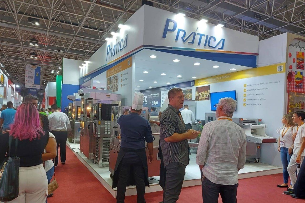 Um grupo de pessoas está em frente a um estande em uma convenção.