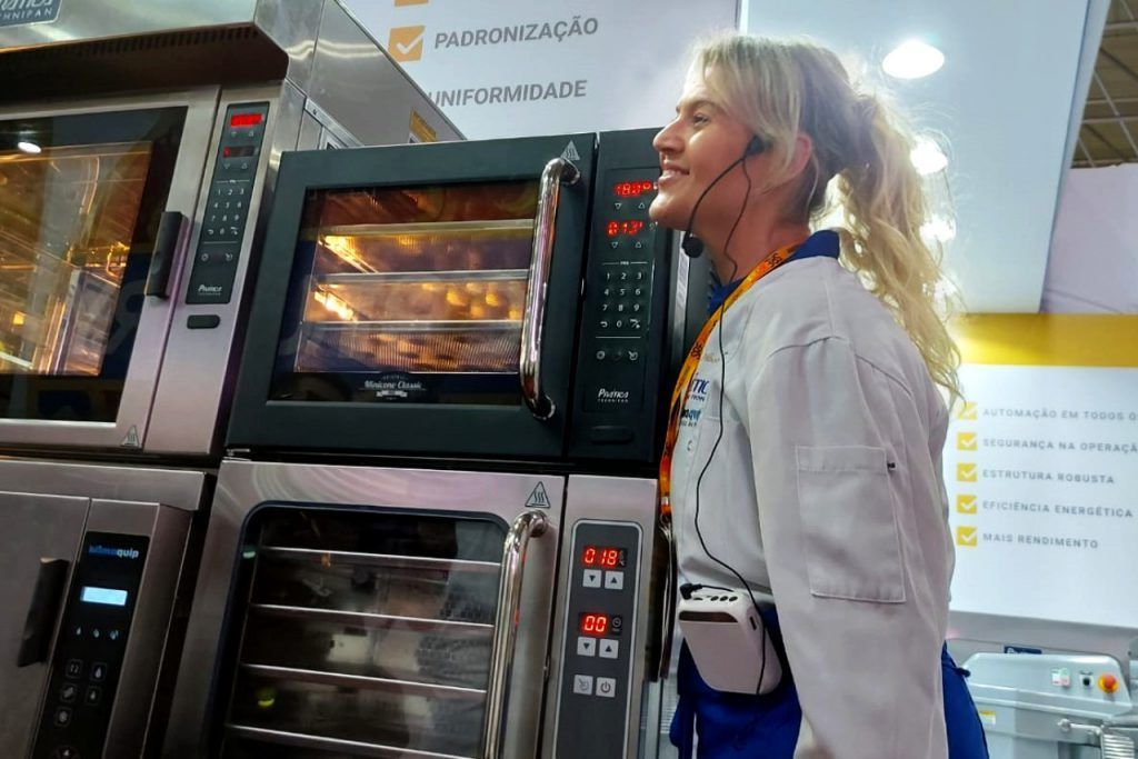 Uma mulher usando fones de ouvido está parada em frente a um forno.