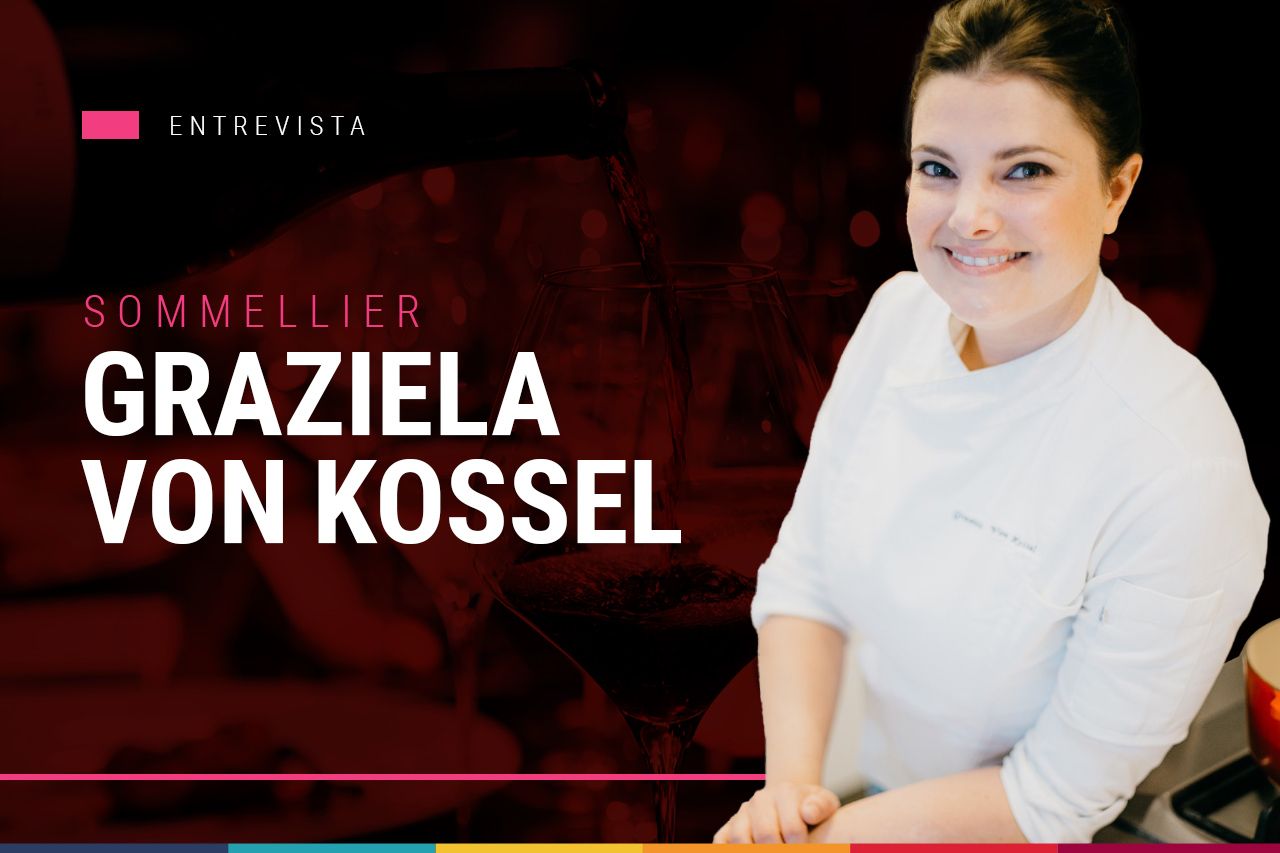Uma mulher sorri em frente a uma placa que diz sommelier graziela von kossel