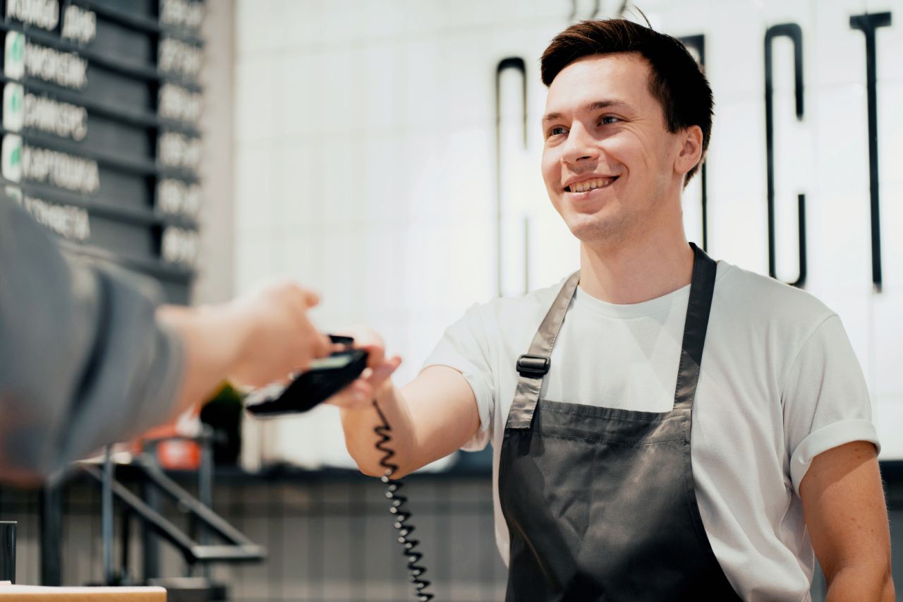 Atendente sorridente recebendo pagamento de um cliente