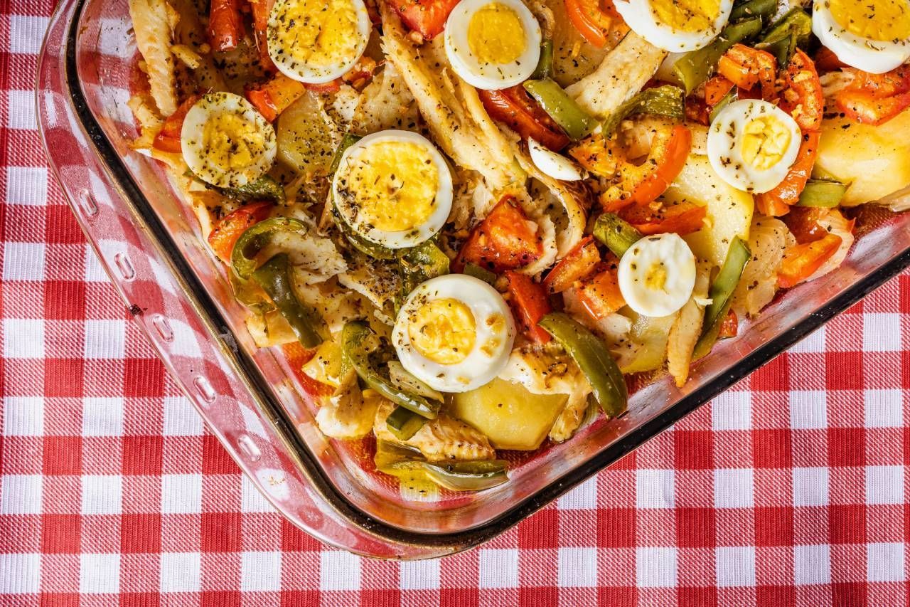 Uma caçarola cheia de vegetais e ovos sobre uma toalha de mesa xadrez.