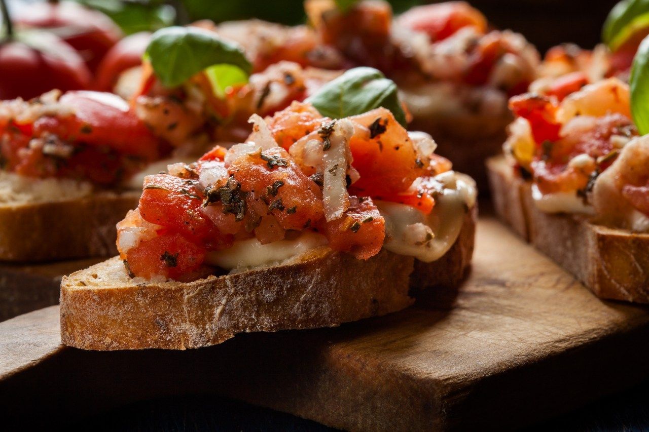 Bruschettas com tomates cebolas e manjericão sobre tábua de madeira