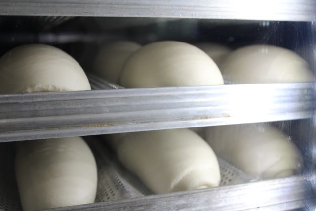 Um monte de bolas de massa estão em uma prateleira na geladeira.