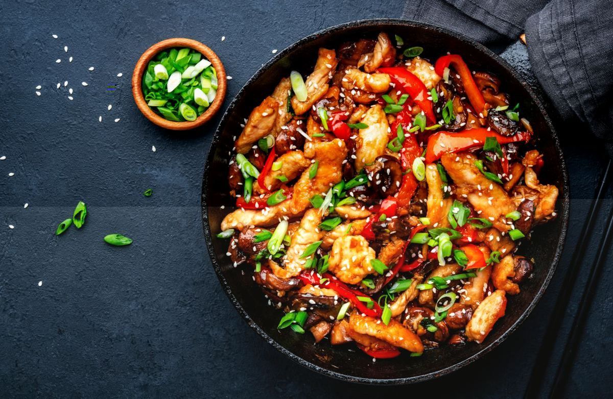 Uma panela cheia de frango e vegetais sobre uma mesa.
