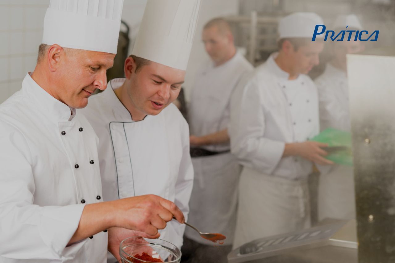 Um grupo de chefs está preparando comida em uma cozinha.