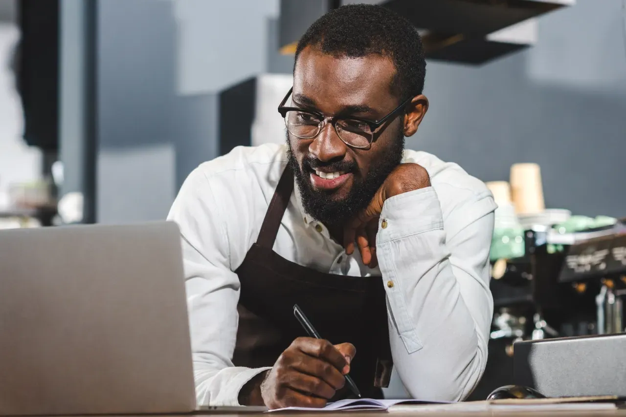 Um homem está sentado à mesa usando um laptop.