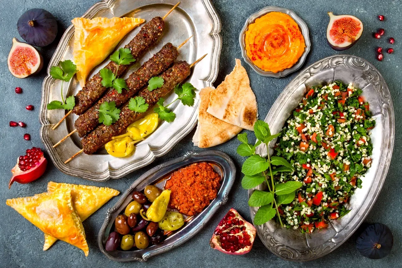 Prato com alimentos halal, incluindo espetos de carne, tabule, pão árabe, homus, azeitonas 